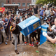 A counter-demonstrator throws a newspaper box at white nationalists at the entrance to Lee Park.